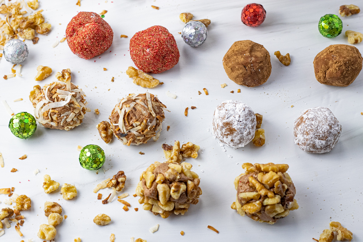 small truffle balls coated in nuts, powdered sugar, cocoa powder, coconut and red sprinkles