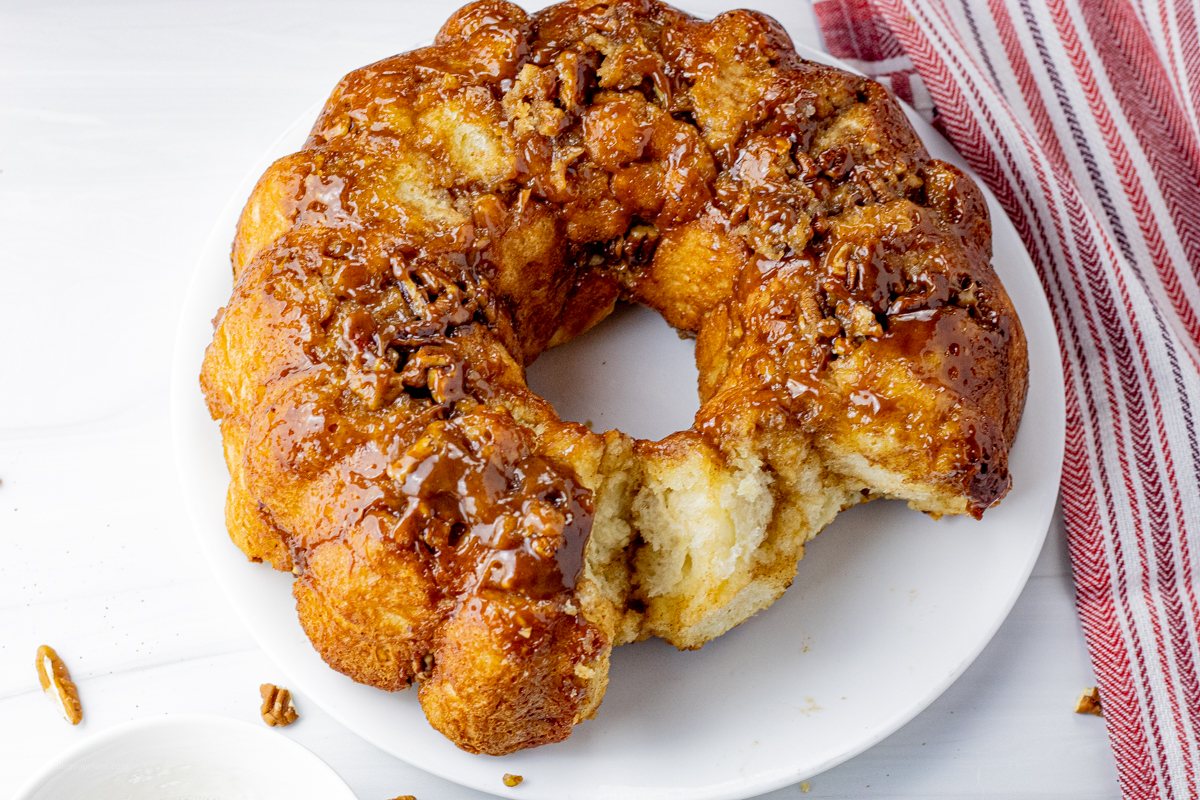 round baked bread topped with caramel sauce with a piece missing
