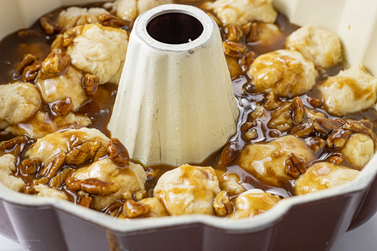 uncooked bread in a bundt cake pan topped with caramel sauce