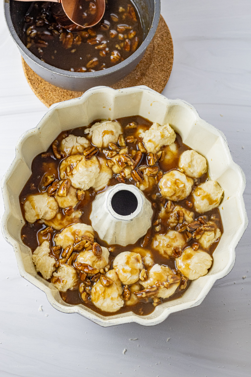 bread dough balls in a bundt pan topped with caramel pecan sauce