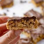 hand holding up oatmeal peanut butter bar topped with chocolate
