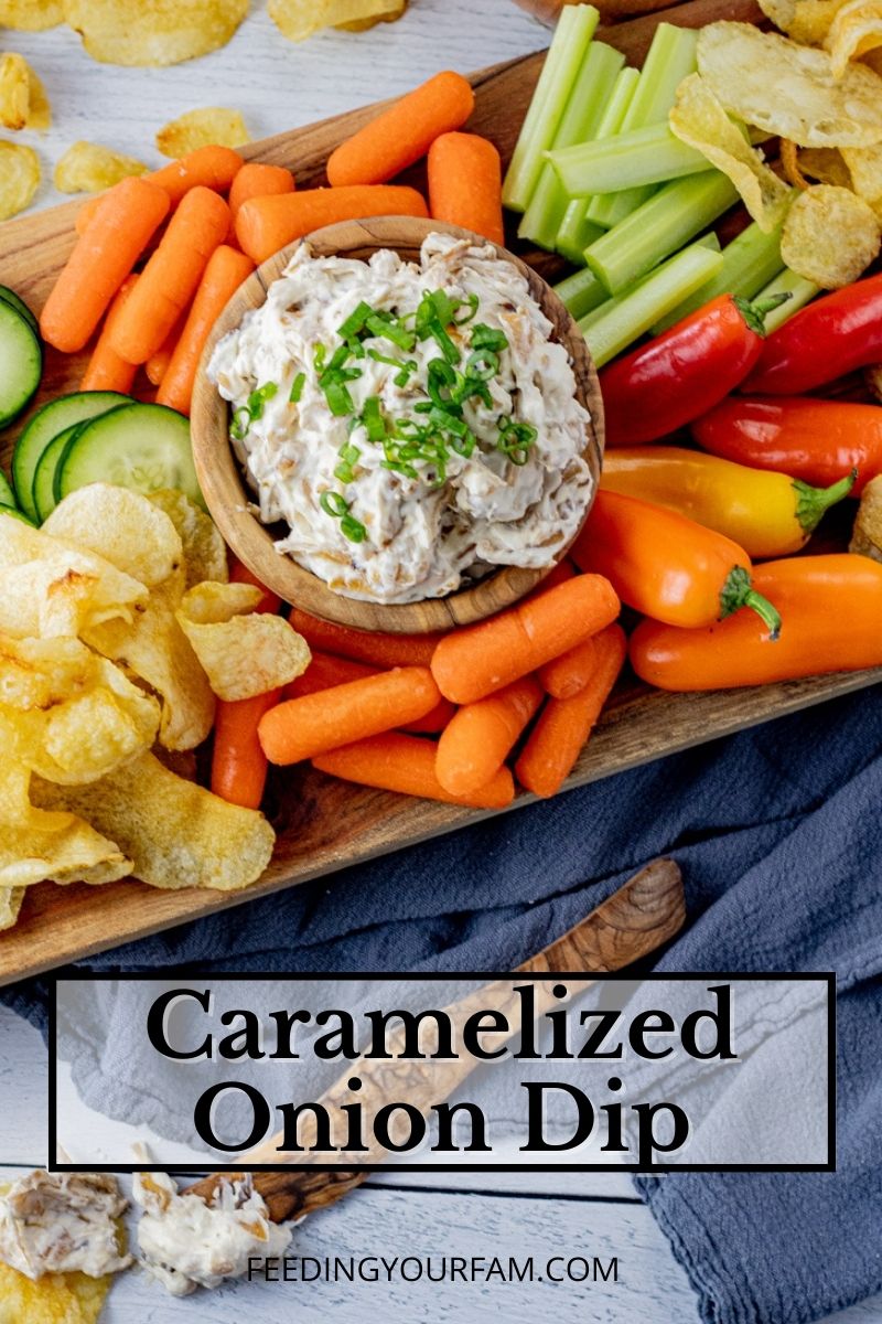 cream cheese onion dip in a wooden bowl surrounded by vegetables and chips