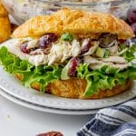 chicken salad with red grapes inside of a buttery croissant with leafy lettuce