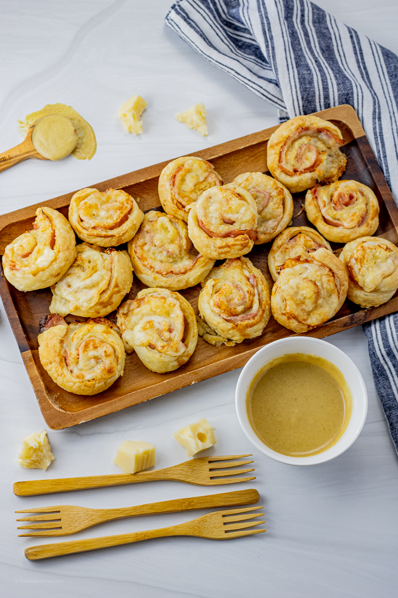 cooked ham and cheese swirled sandwiches on a wooden serving platter