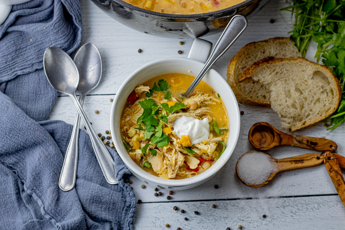 bowl of white chili with chicken topped with sour cream and cilantro