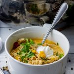 bowl of chicken chili with a dollop of sour cream and cilantro