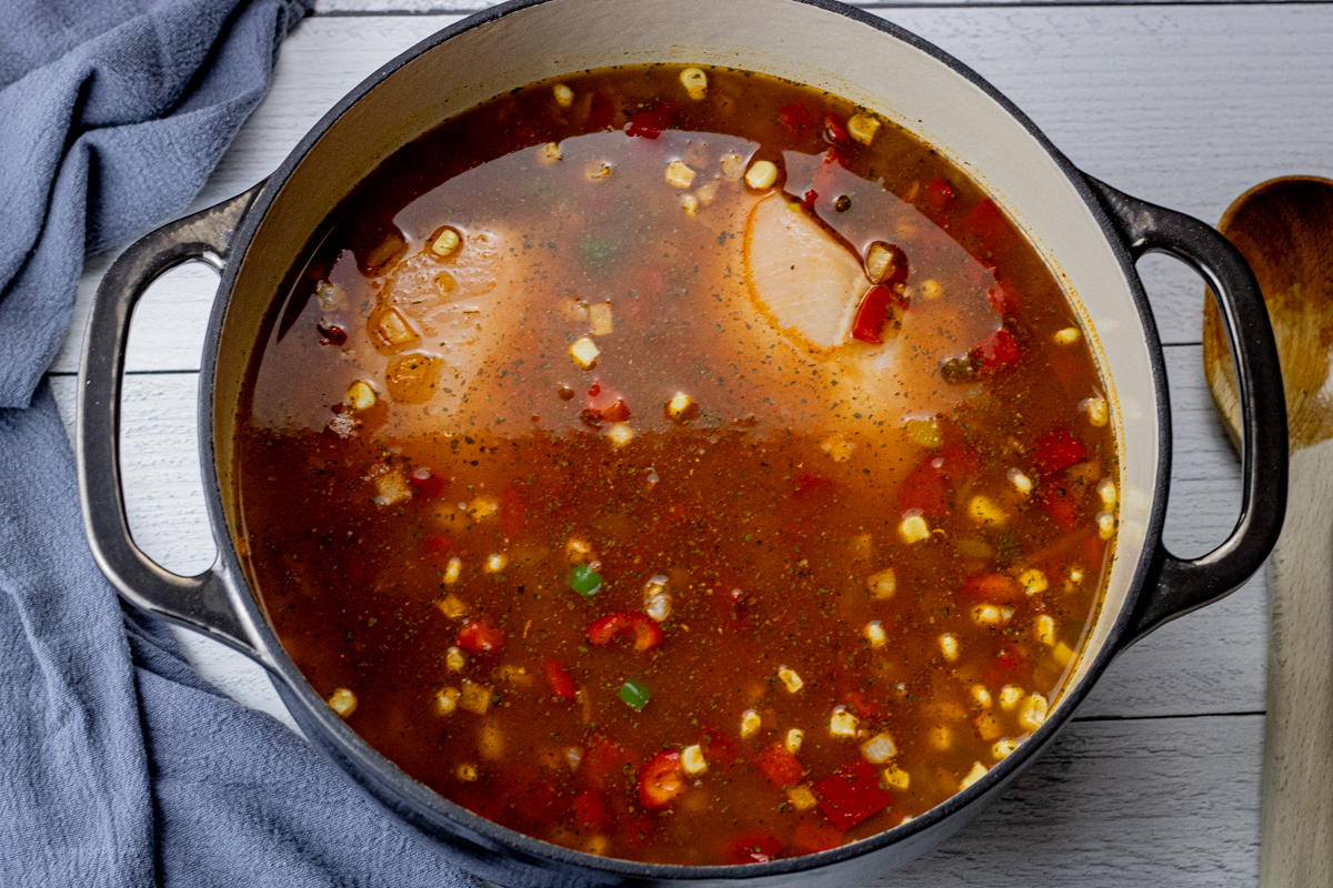 raw chicken in chicken broth in a large pot