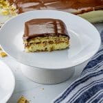 slice of chocolate eclair cake topped with chocolate frosting on a white plate