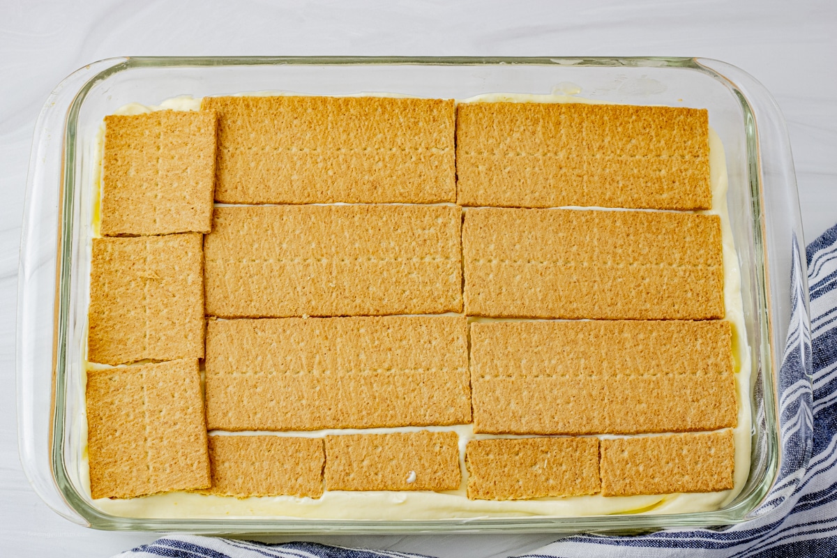 glass baking dish with a layer of graham crackers over a layer of vanilla pudding