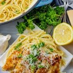crispy chicken on top of linguine pasta on a white plate