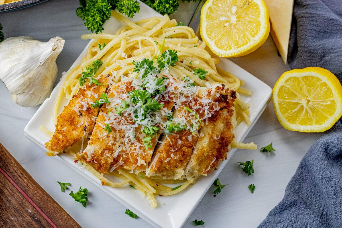 bread crumb coated chicken sliced, and placed on top of cooked pasta