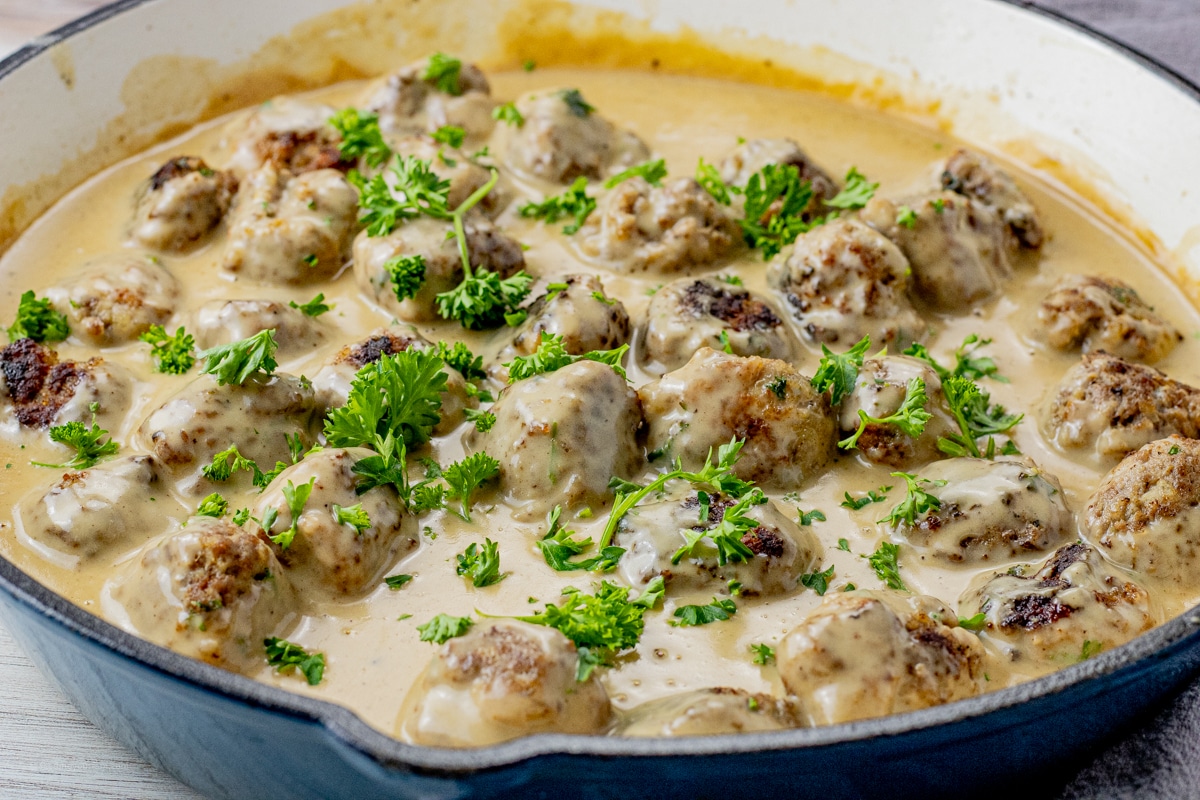 swedish meatballs in a brown gravy sauce topped with chopped parsley