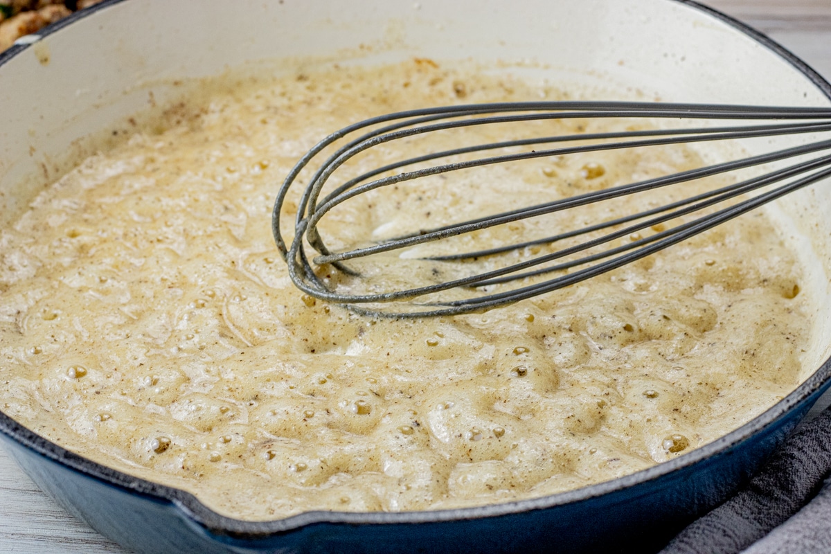 a whisk in a pan whisking together butter and flour that is bubbling hot