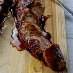 sliced, glazed pork tenderloin on a wooden cutting board