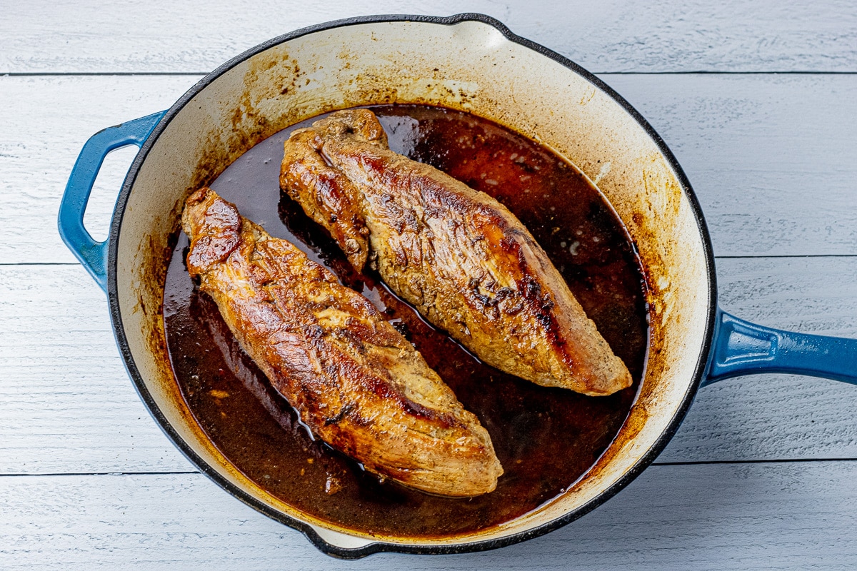 two pork tenderloins in a cast iron pan with maple glaze