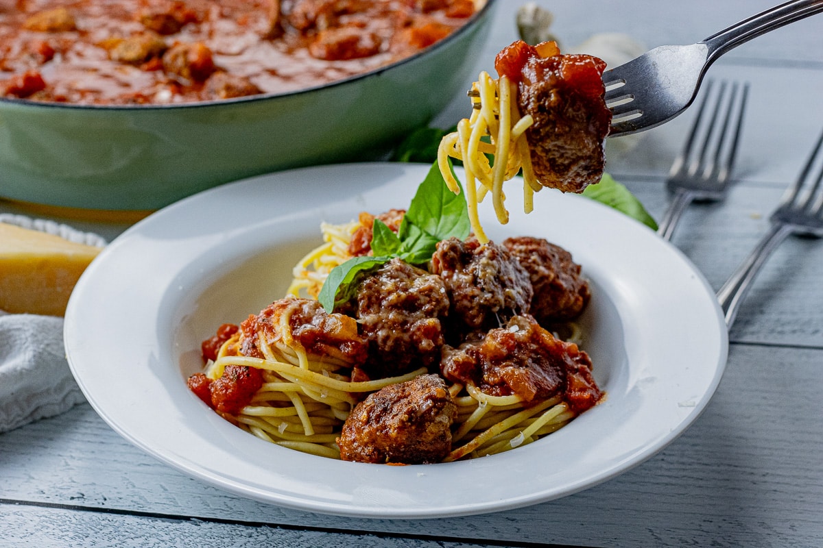 fork lifting up a piece of spaghetti and meatball
