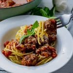 fork lifting a meatball out of a bowl of spaghetti and meatballs