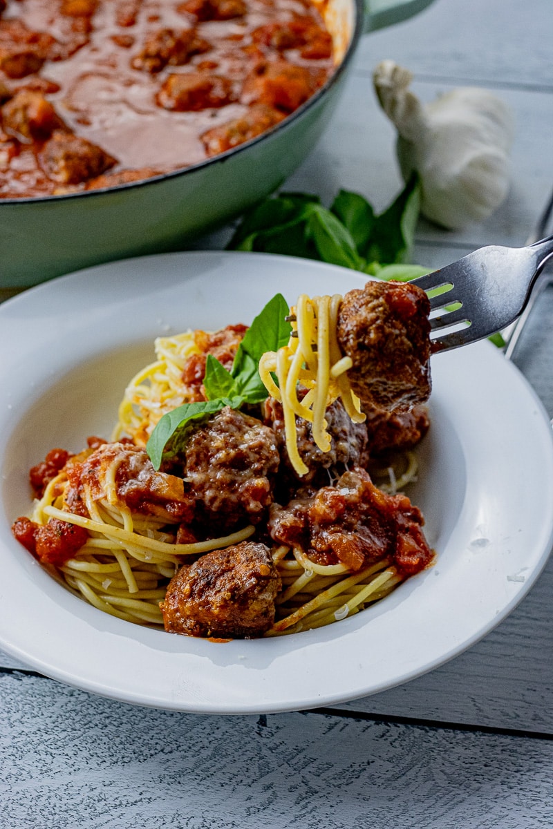 fork holding a meatball with spaghetti noodles