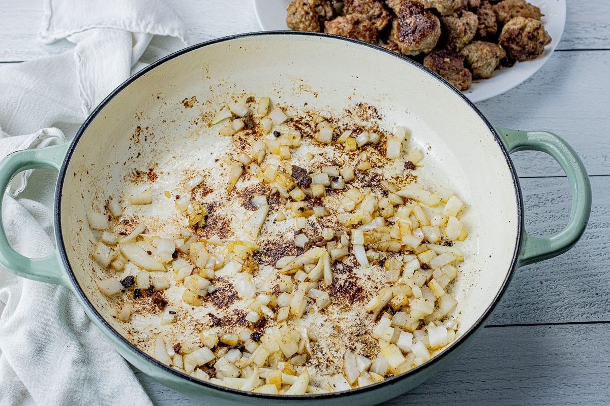 cooked onions in the bottom of an enameled pan