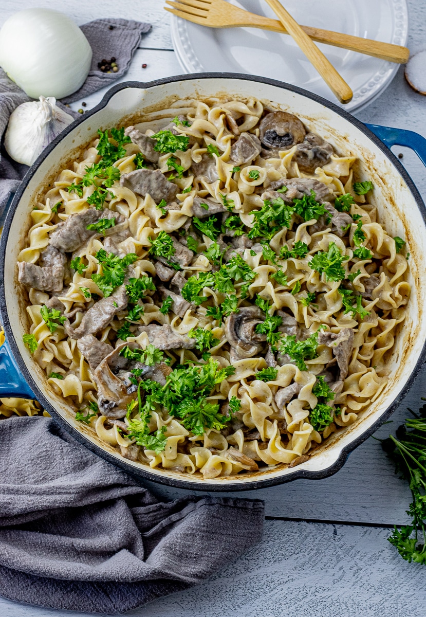 large skillet filled with egg noodles mixed with beef stroganoff