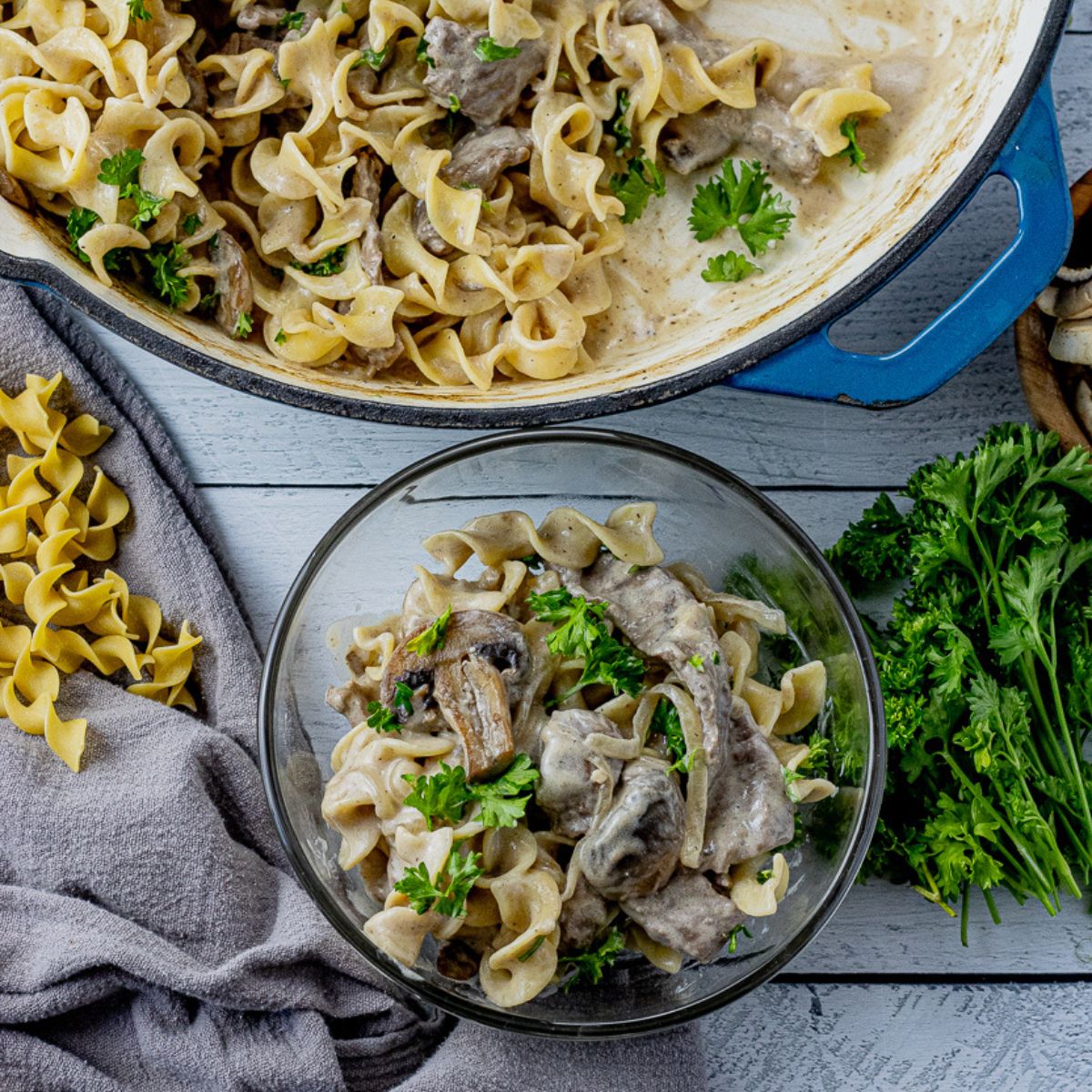 glass bowl with some beef stroganoff in it in front of a large skillet with more in the pan