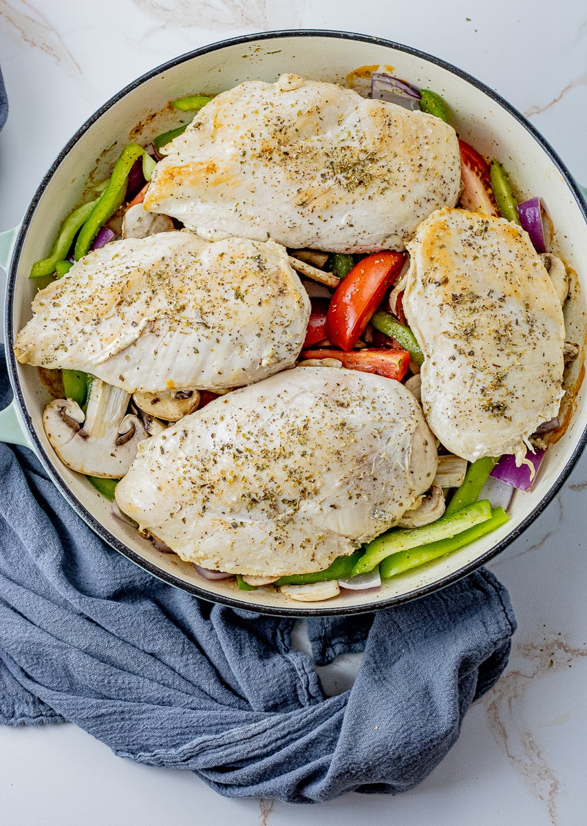 4 chicken breast on top of tomatoes, green peppers, onions and mushrooms