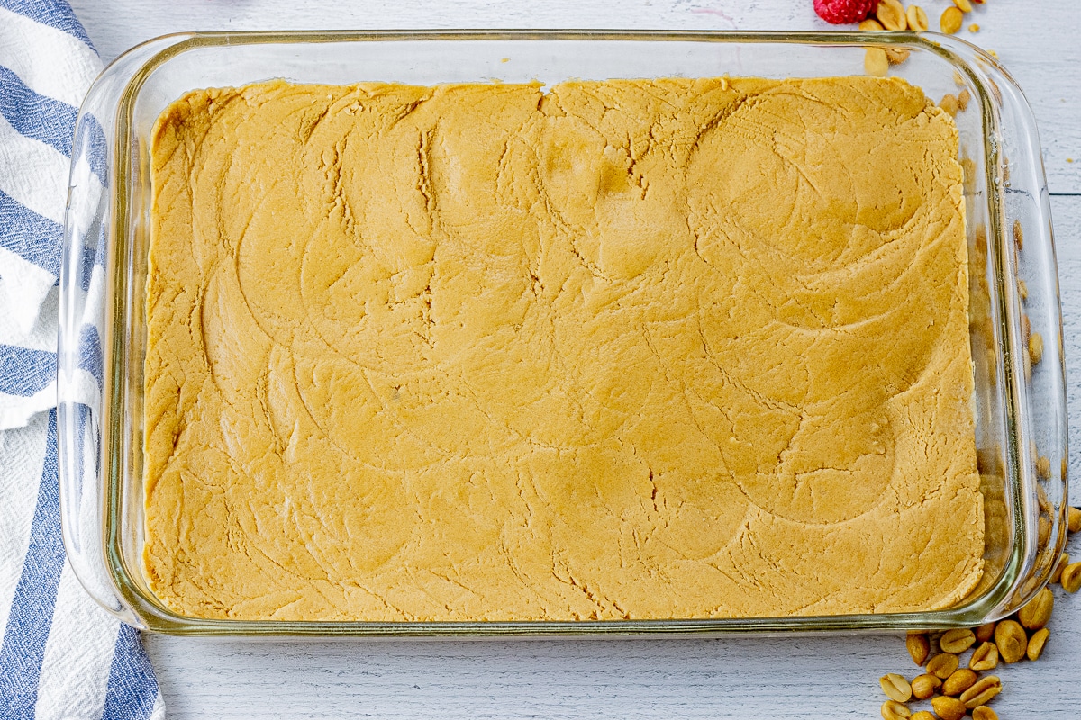 peanut butter cookie dough pressed into the bottom of a 9 x 13 inch glass baking dish