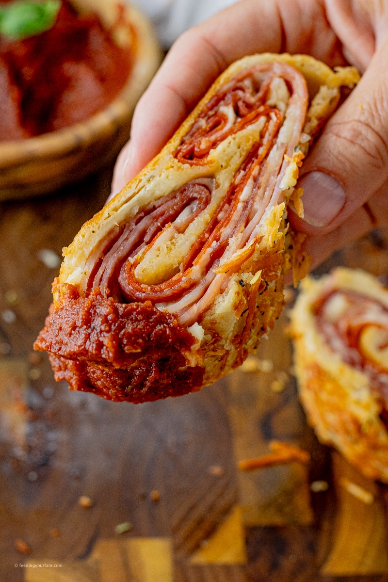slice of stromboli rolled up with ham, sausage, salami and cheese dipped in pizza sauce