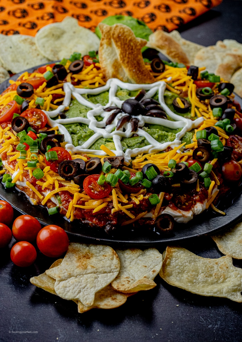 layered Halloween dip with a spider web made from sour cream on top