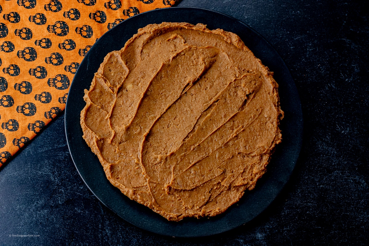 black plate with refried beans spread on it