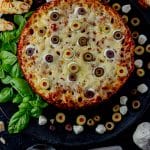 baked rigatoni topped with melted cheese and sliced olives to look like eyeballs