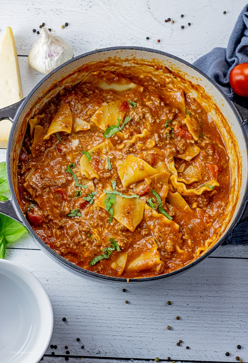 lasagna soup in a large dutch oven pot with chopped basil on top