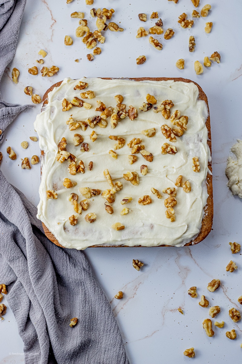maple cake topped with vanilla frosting and chopped pecans
