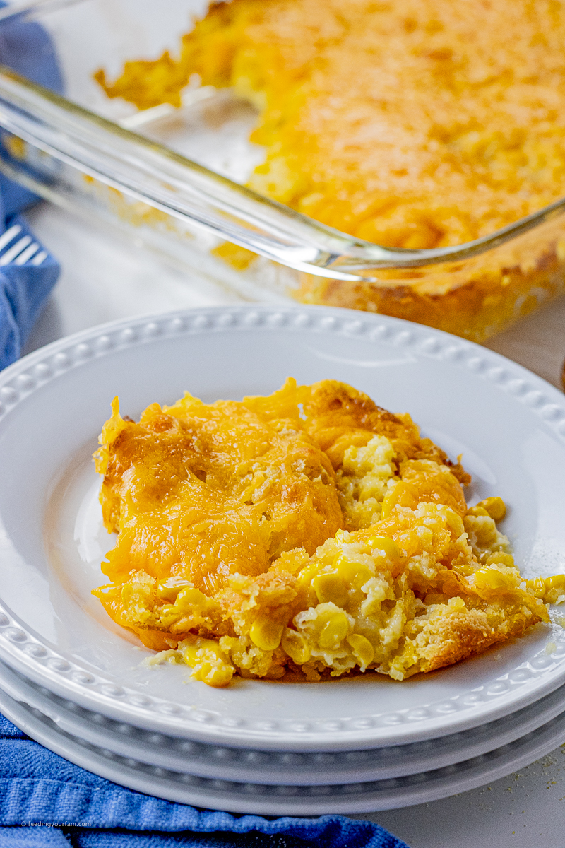 corn casserole topped with cheddar cheese on a white plate