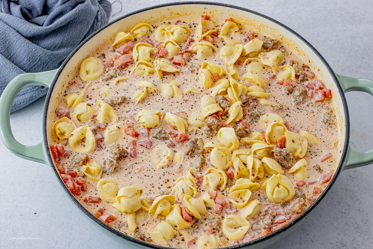tortellini and sausage cooking in a creamy sauce