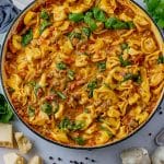 big pan of tortellini in a creamy, tomato sausage sauce with spinach