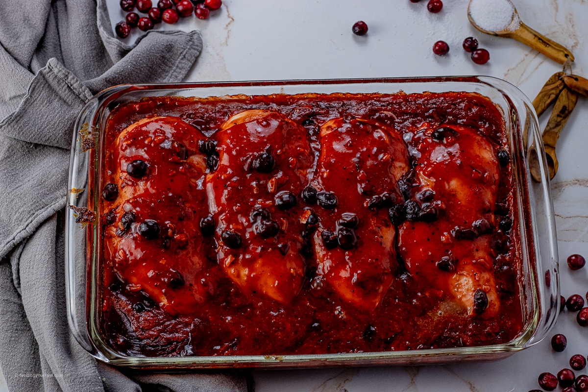 glass baking dish with cooked chicken in a cranberry sauce