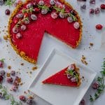 cranberry tart with a slice out, topped with sugared cranberries and rosemary sprigs