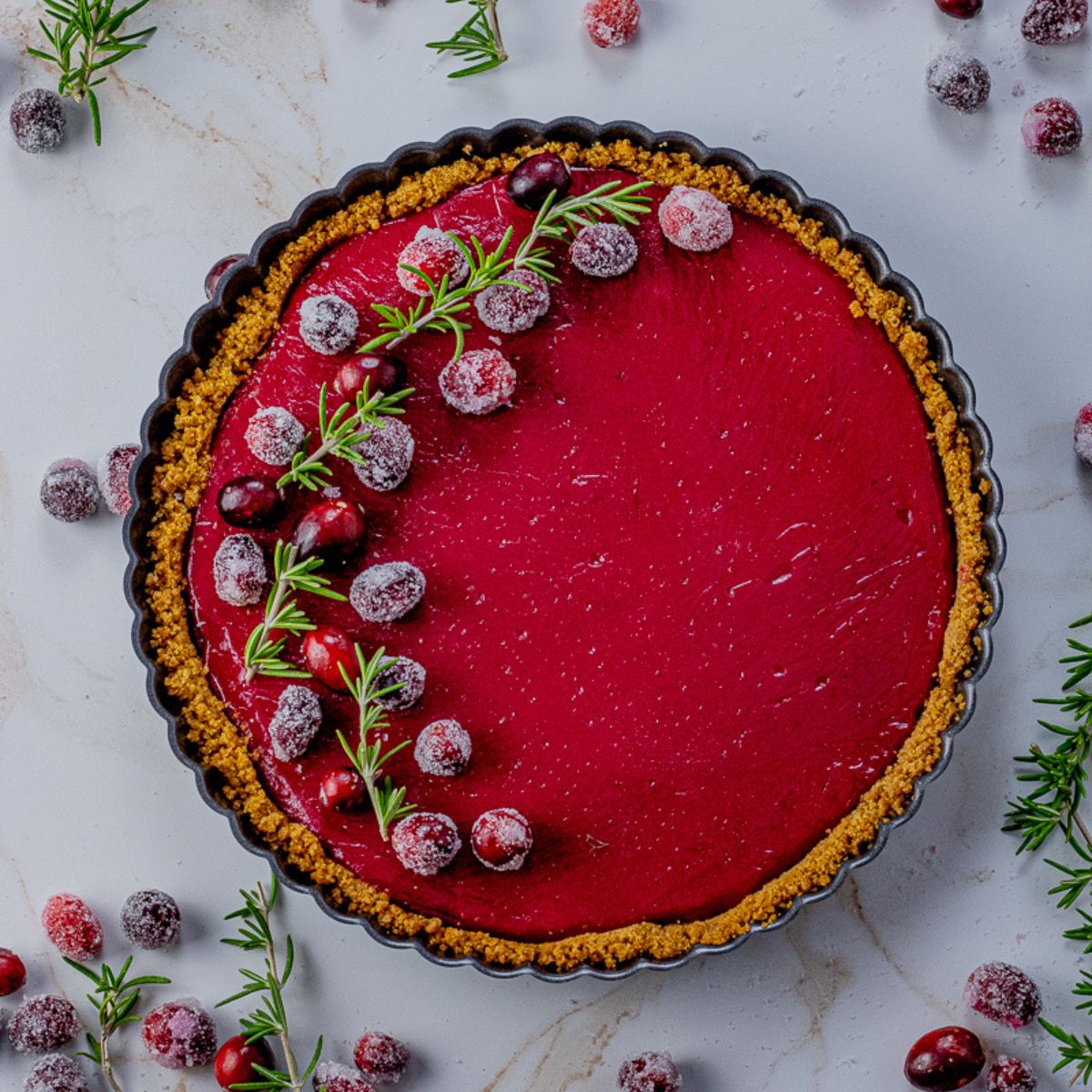 cranberry tart topped with sugared cranberries and rosemary sprigs