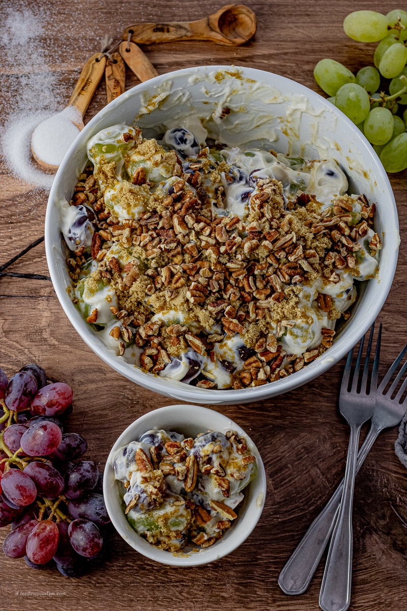 This Grape Salad Recipe is a simple and quick side dish that is loaded with red and green grapes in a creamy dressing covered in brown sugar and pecans. Perfect for potlucks and family get togethers! salad made with grapes in a cream cheese dressing topped with brown sugar and pecans