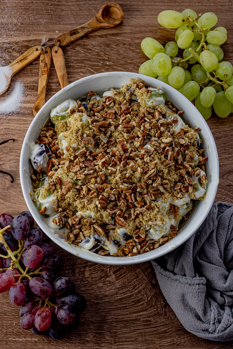 red and green grape salad topped with a cream cheese dressing, brown sugar and pecans