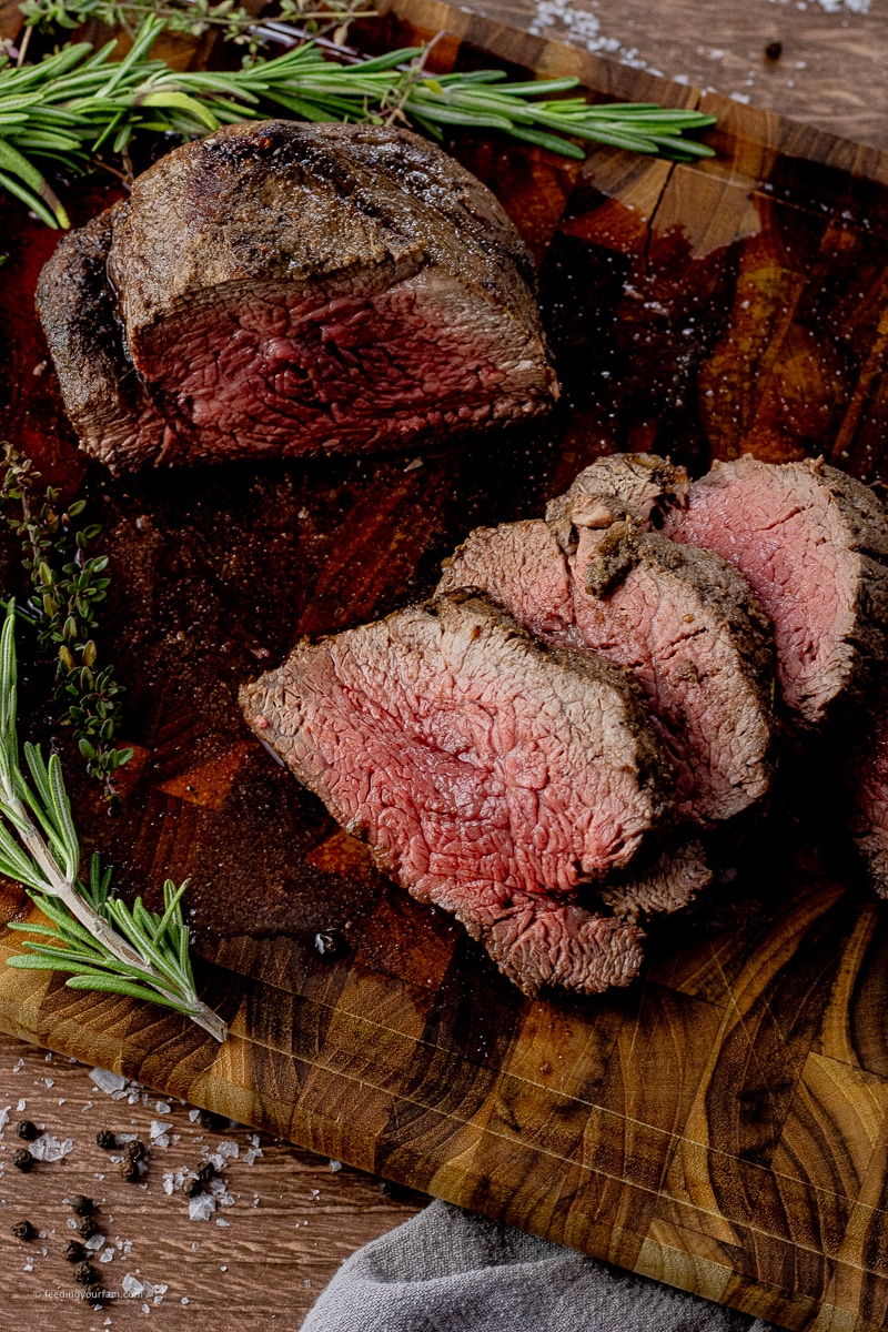 sliced beef tenderloin on a wooden cutting board