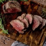 sliced beef tenderloin on a wooden cutting board