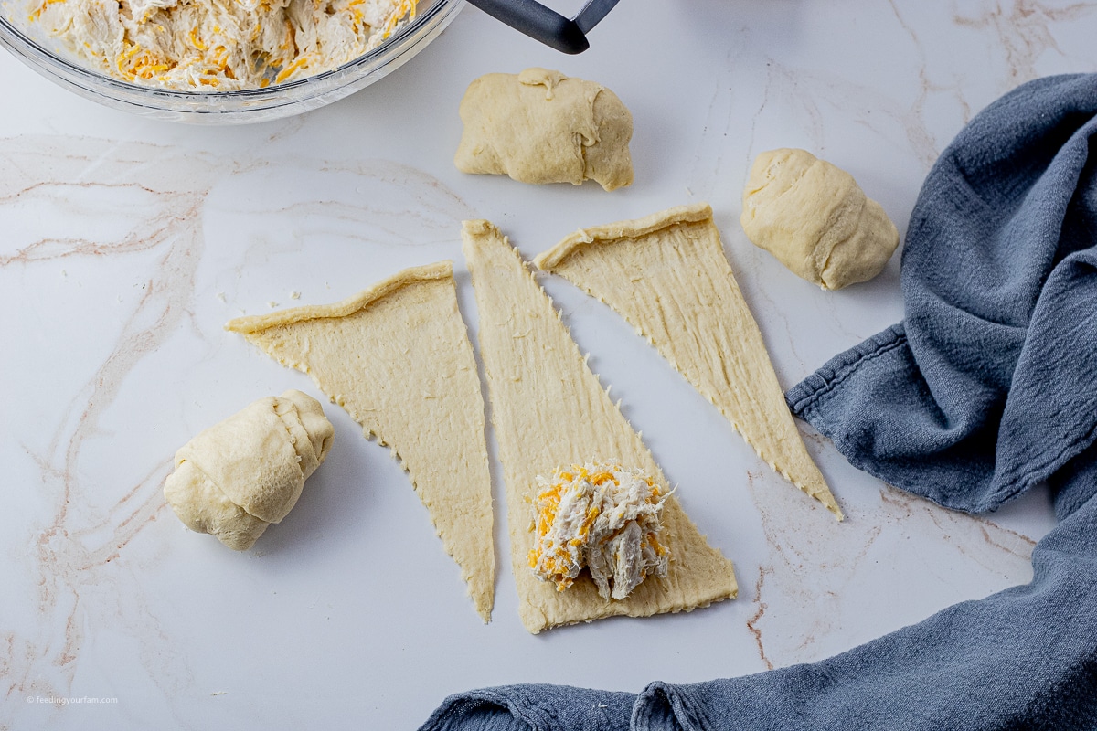 shredded chicken with cheese in an unfolded crescent roll dough strip