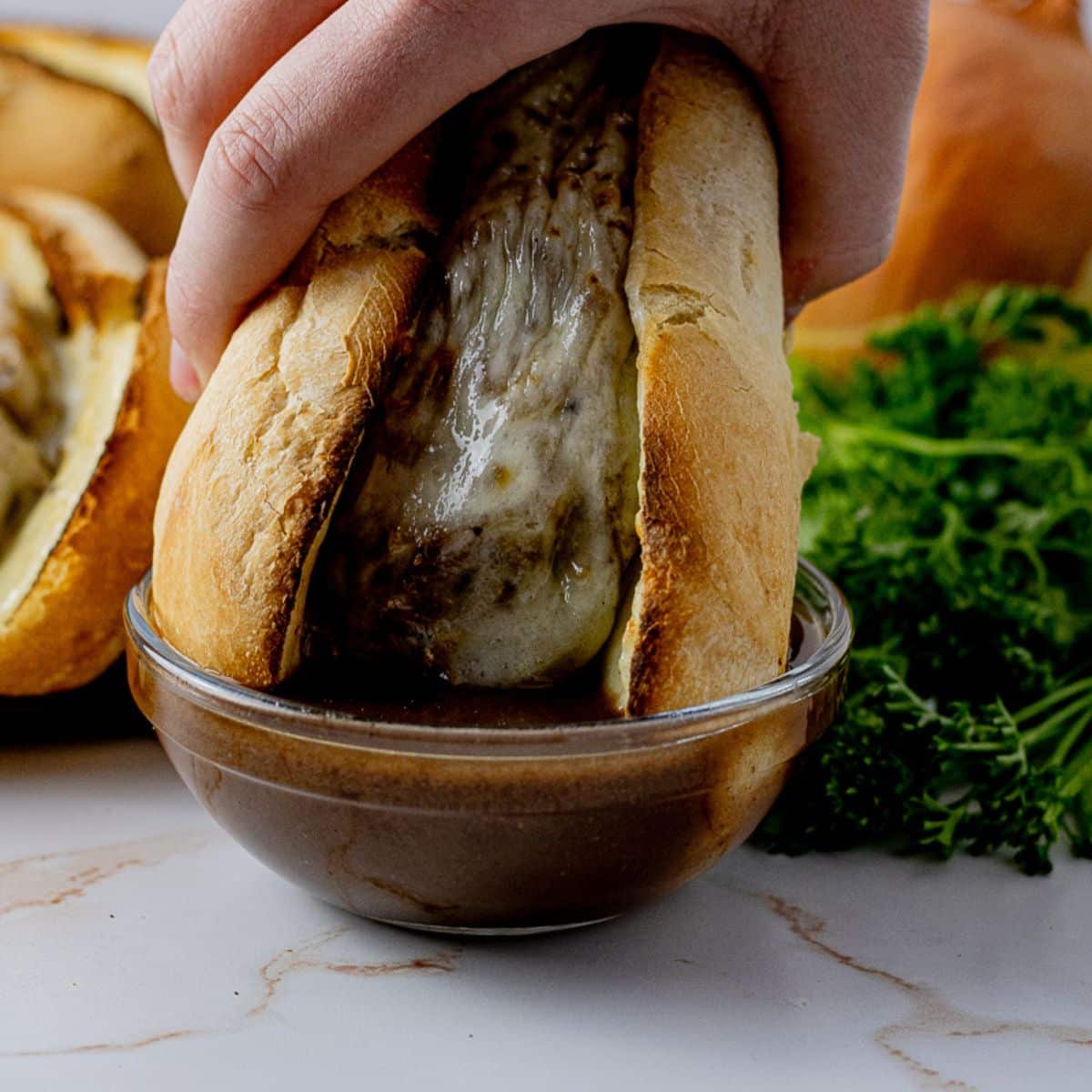 dipping a french dip sandwich into au jus