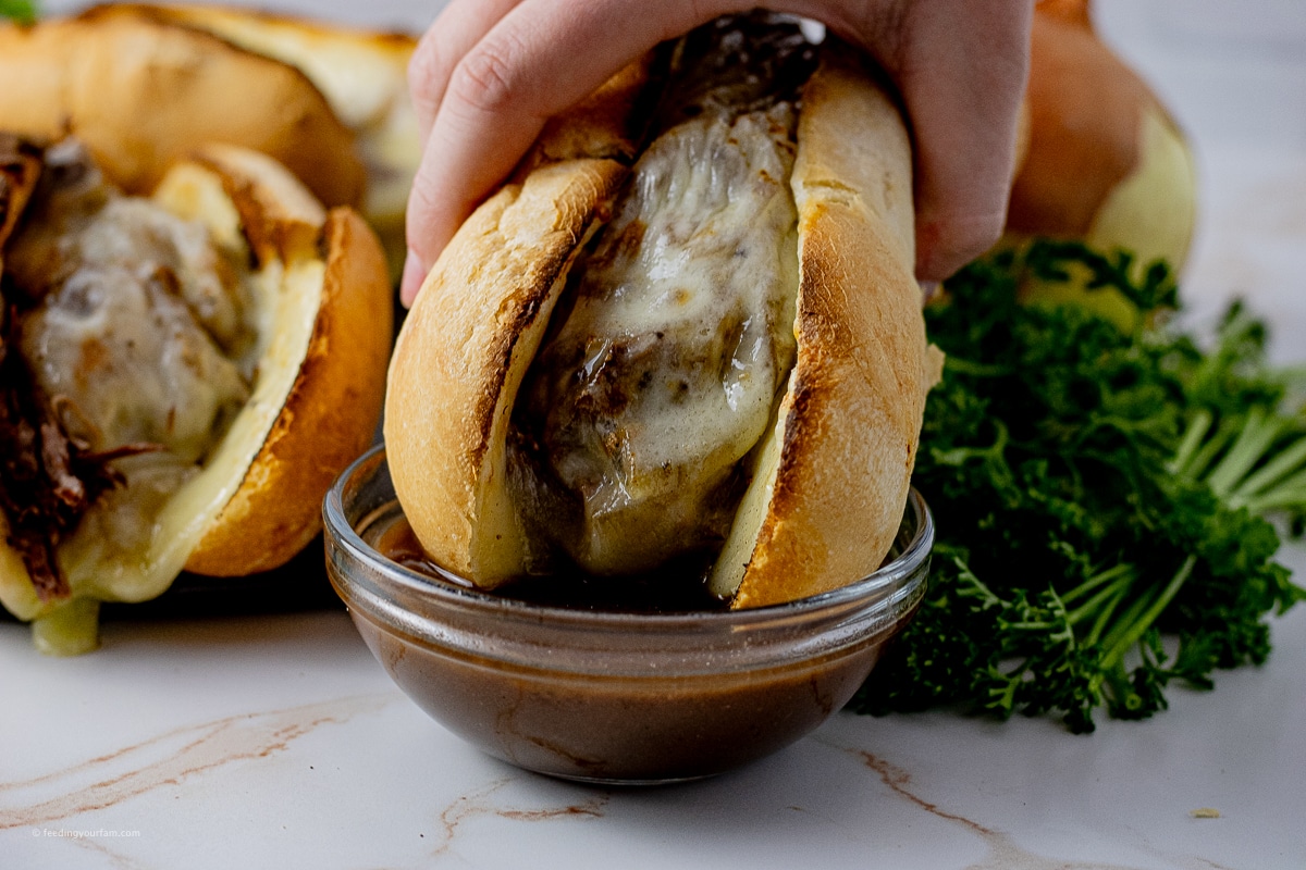 dipping a shredded beef sandwich into some au jus