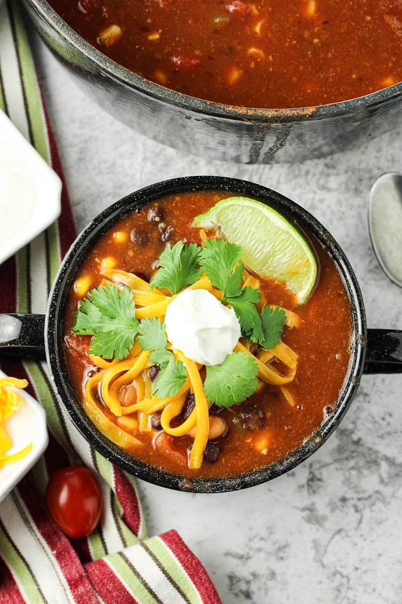 taco soup in a bowl topped with cilantro, sour cream and shredded cheese easy 8 can taco soup recipe