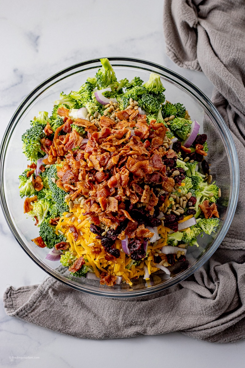 ingredients for a broccoli salad in a large glass bowl