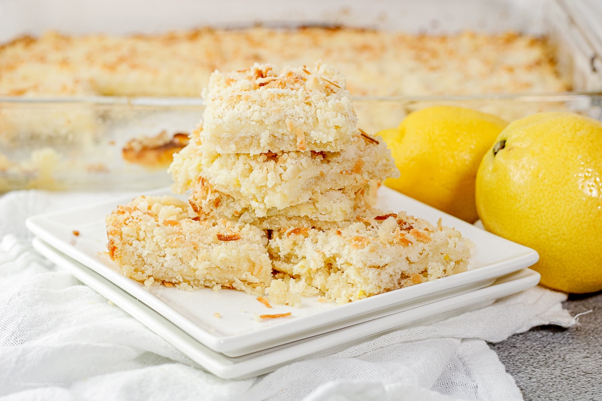 coconut lemon bars stacked on a white plate 