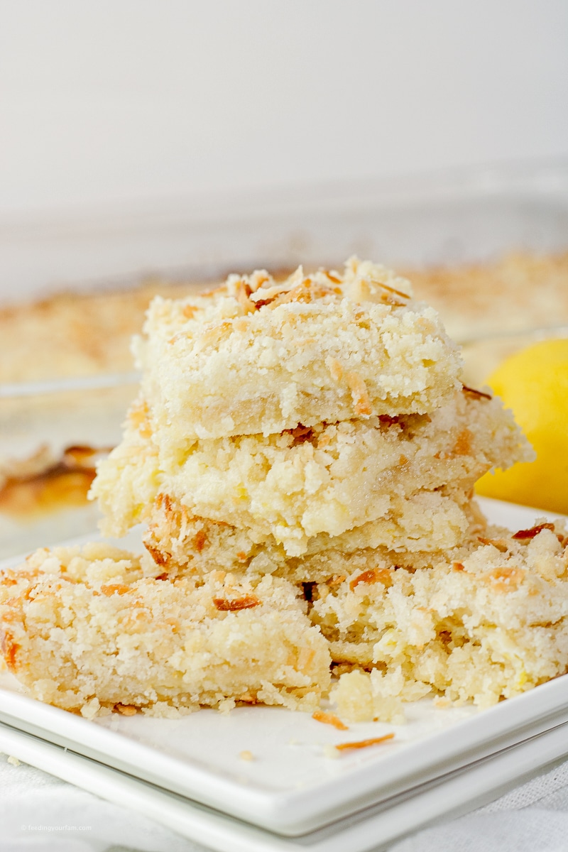 sweet, cookie bars made from lemon and coconut in a stack on a white plate